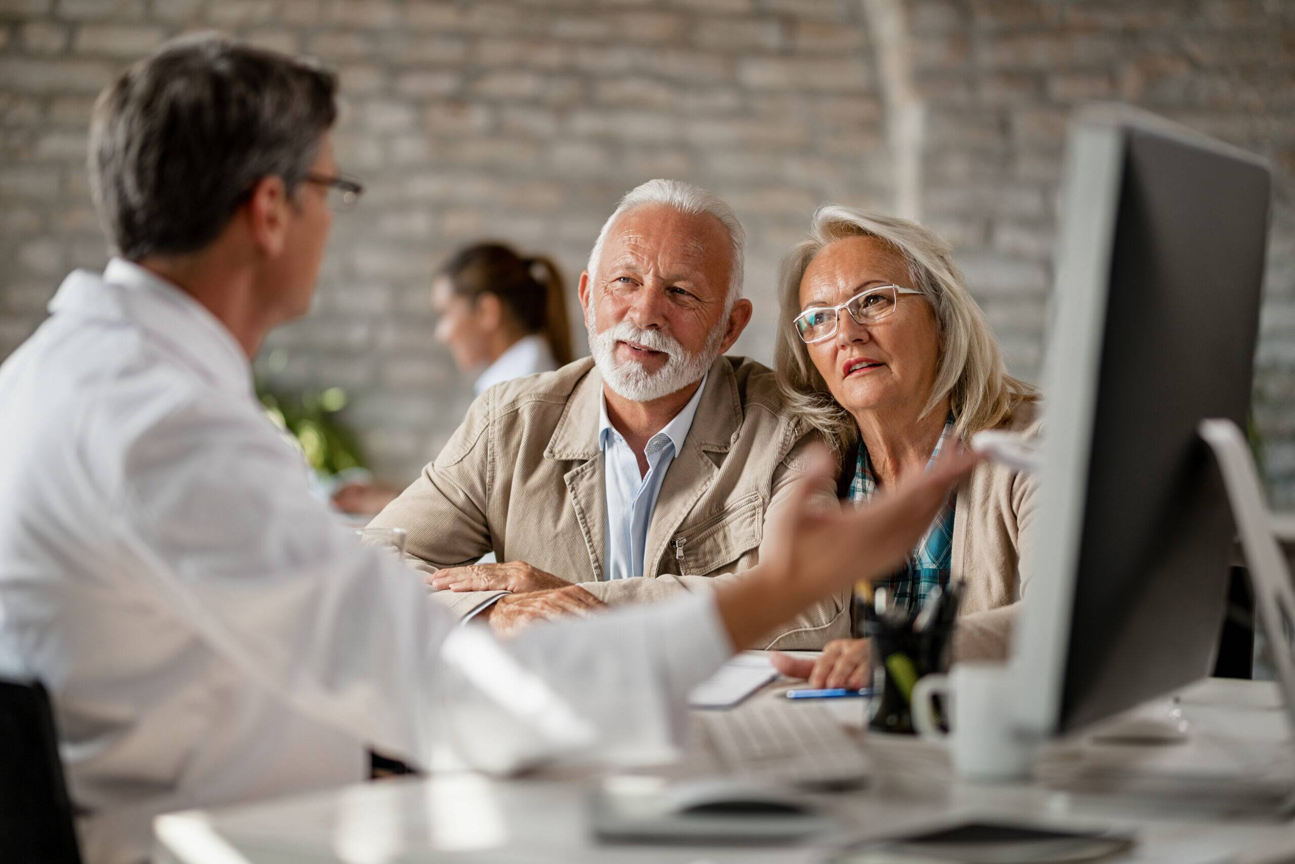 Senior couple talking with a doctor about their medical records while having consultations at clinic.